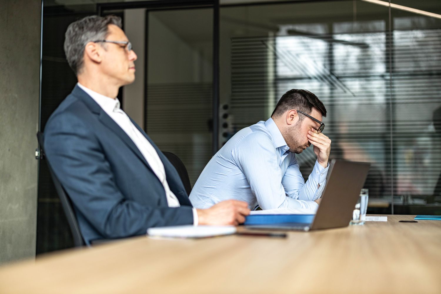 A board member shows frustration as they push up their glasses and rub their eyes after learning the company will be late filing forms with the Securities and Exchange Commission.
