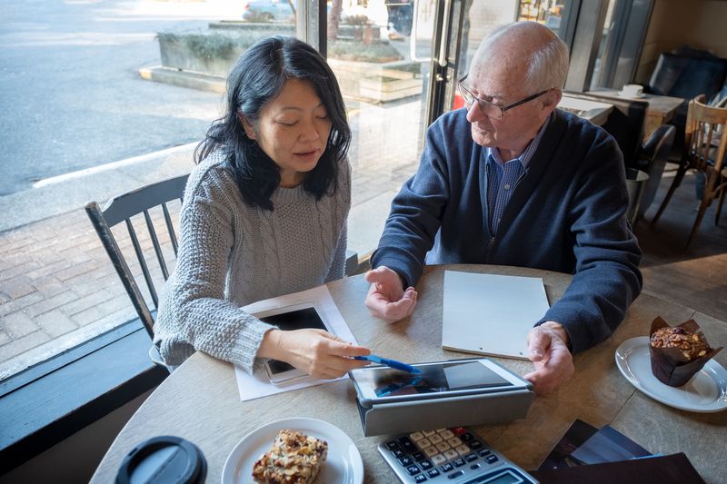 Elderly couple looking at finances on a digital tablet over breakfast