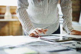 A businesswoman looking at digital tablet on table in office.