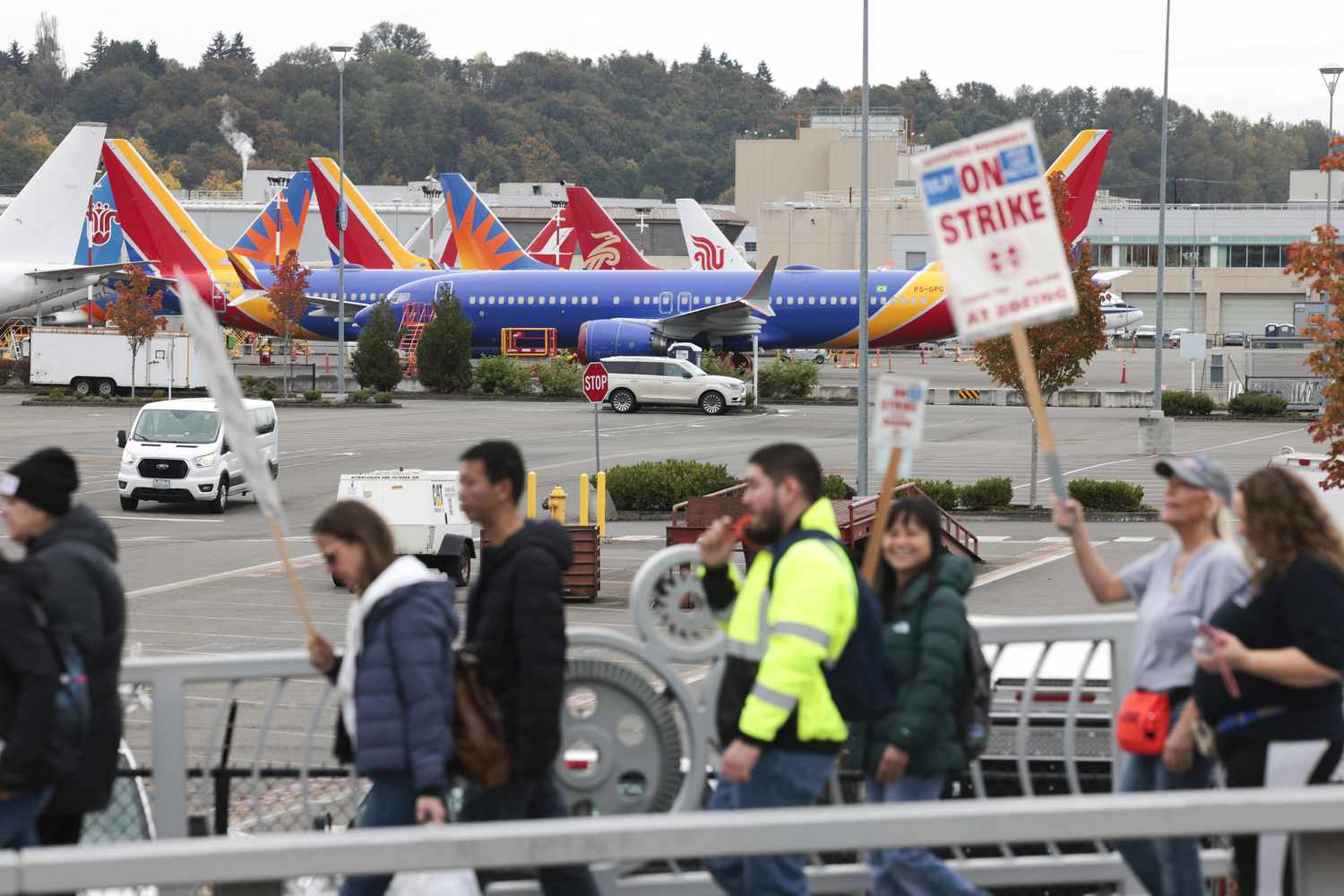 People carry strike signs as they walk past parked Boeing 737 planes near Boeing Field following a strike rally for the International Association of Machinists and Aerospace Workers (IAM) at the Seattle Union Hall in Seattle, Washington, on October 15, 2024.