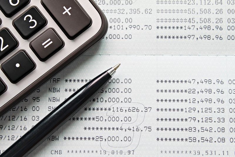 A top view or flat lay of calculator and pen on savings account passbook or financial statement.