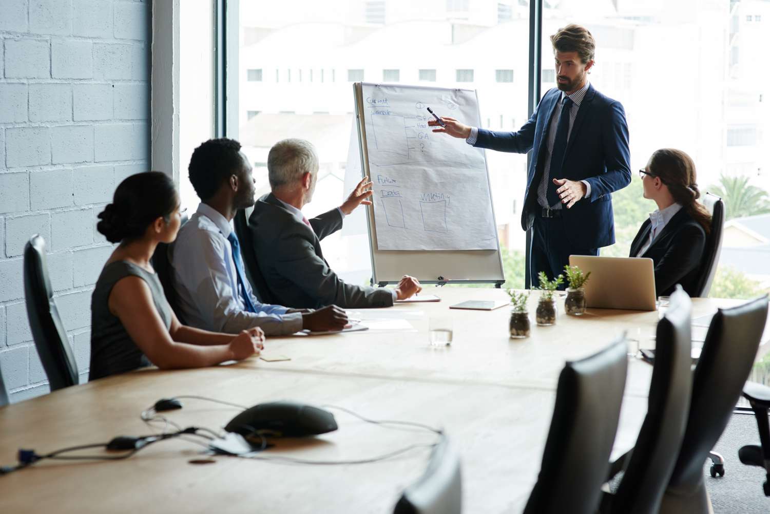 Business people sitting round a table listening to a presentation