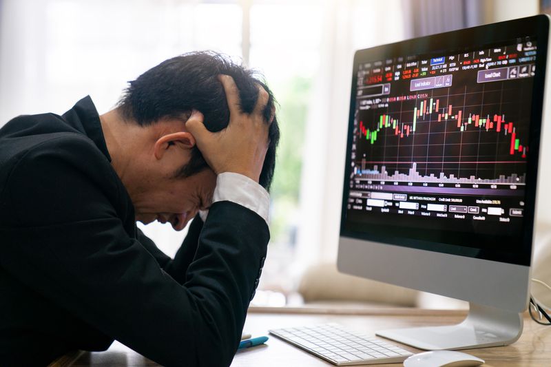 A trader holding the wrong side of an options contract holds their head in despair as a computer screen shows the underlying stock in a sharp decline.