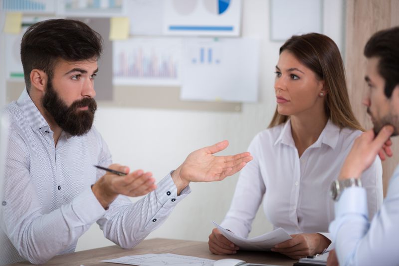 Three people sitting and discussing about credit repairing at an agency