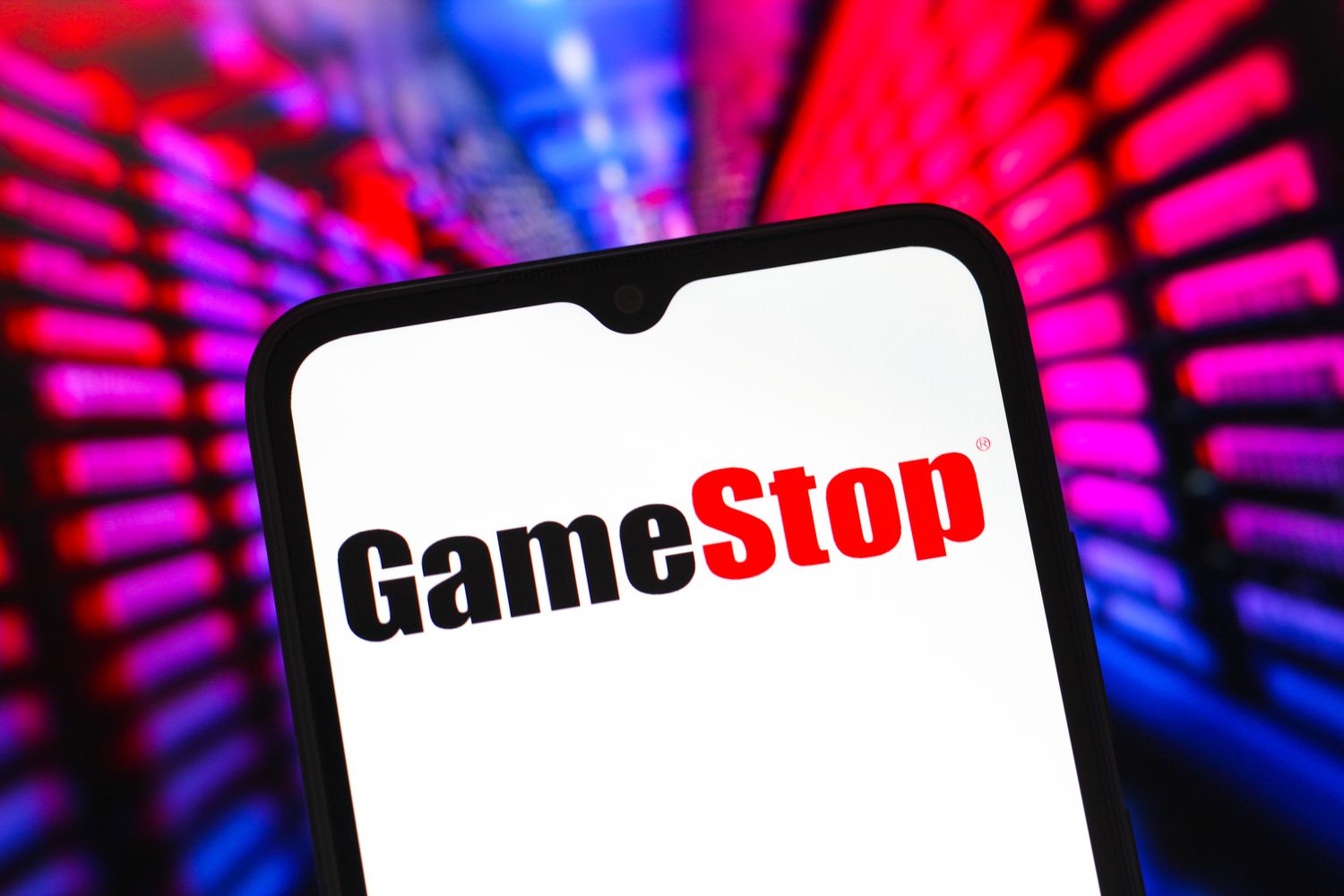 The black and red GameStop logo is seen on a phone screen with a blue and red background.