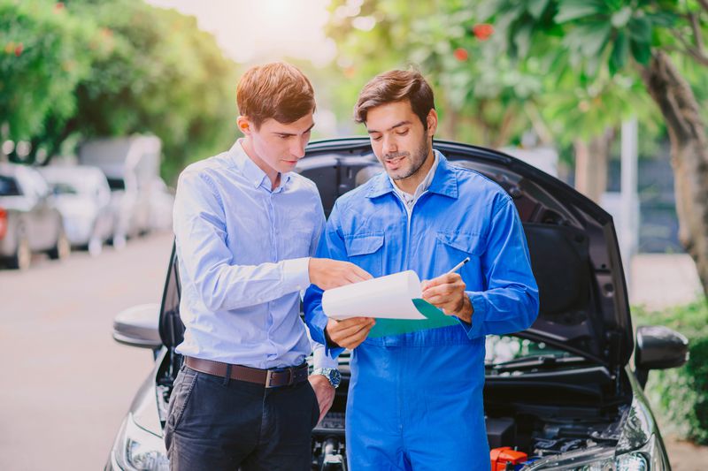 Car insurance agent and customer in front of a car