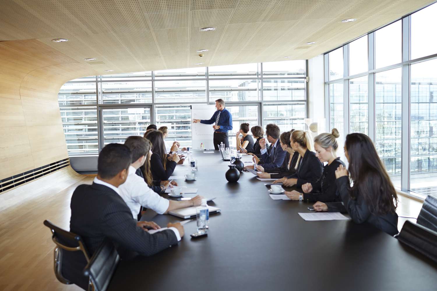 Attendees at an executive board meeting listen to financial information about company improvment as part of their share purchase offer.