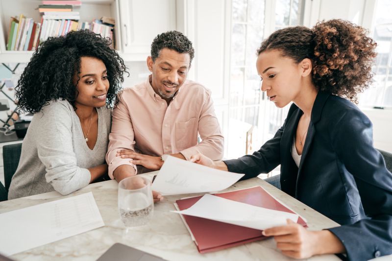Couple talks to a businesswoman about getting tuition insurance for their child