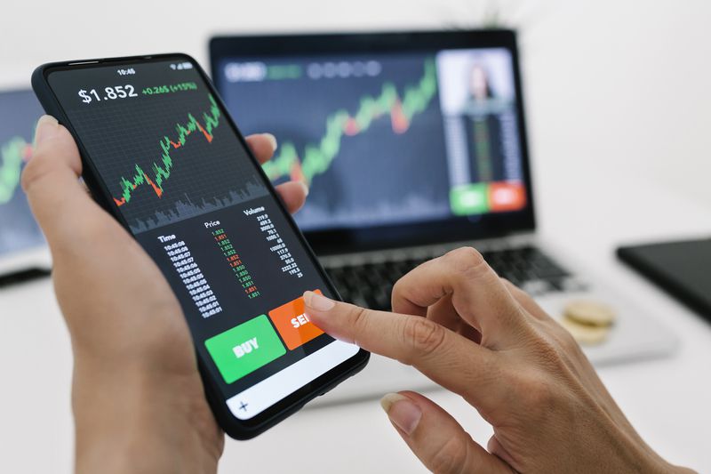Image showing hands holding a mobile phone displaying a trading app.