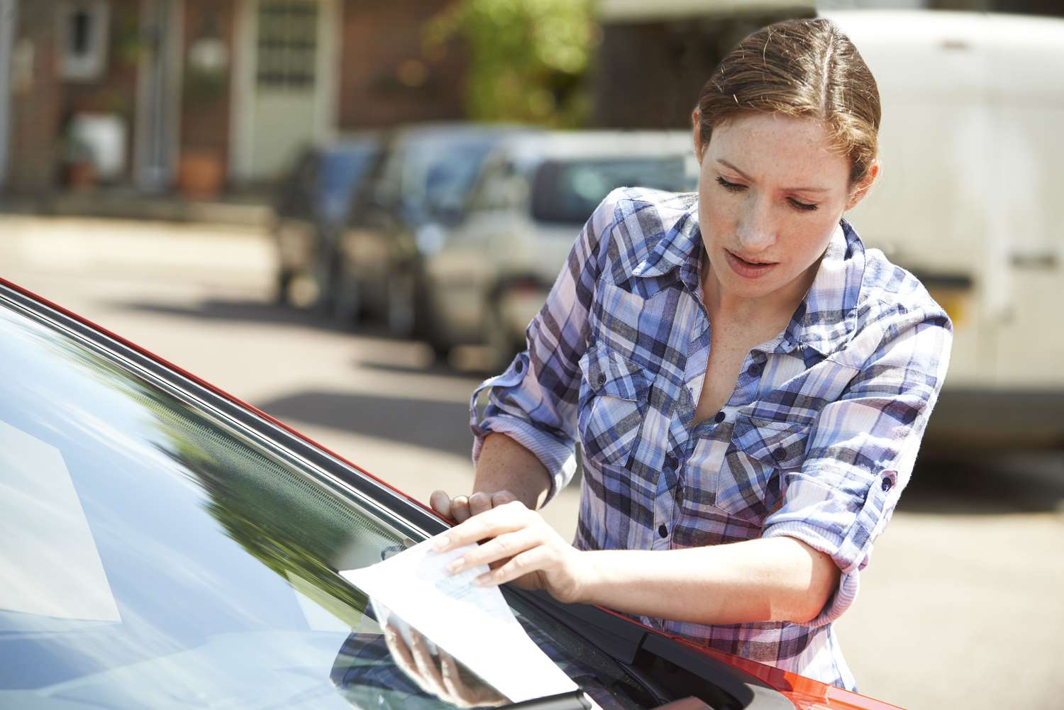 Woman looking at a parking ticket on her windshield