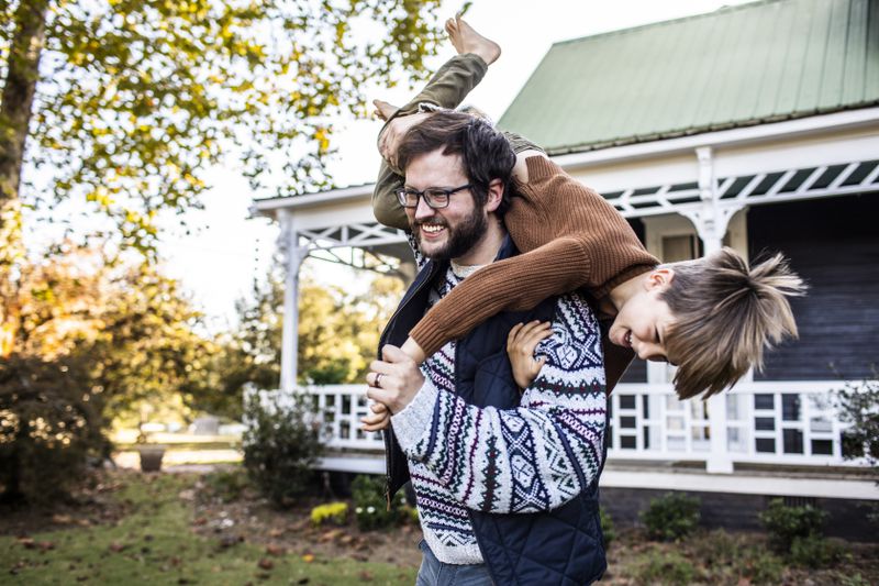 Father playing with son in front of house
