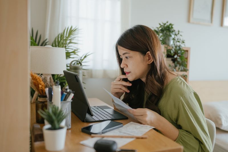 Person looking at paperwork while working on a computer