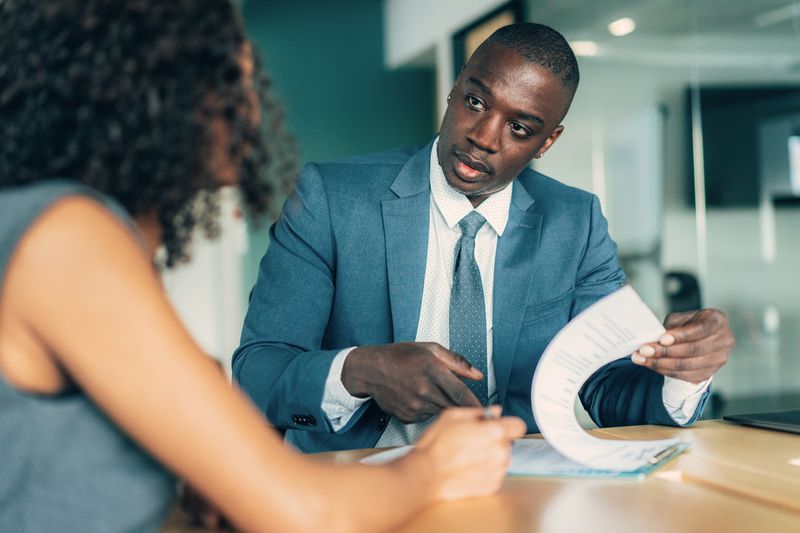 Two People Discuss Assets in an Office