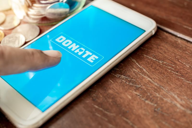 Finger pressing donate button on mobile phone