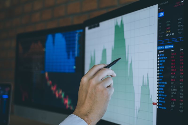 A male hand pointing a computer screen with charts.