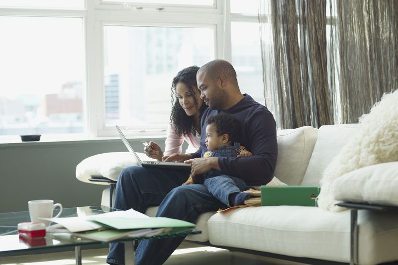 Couple with baby on a sofa looking at a laptop