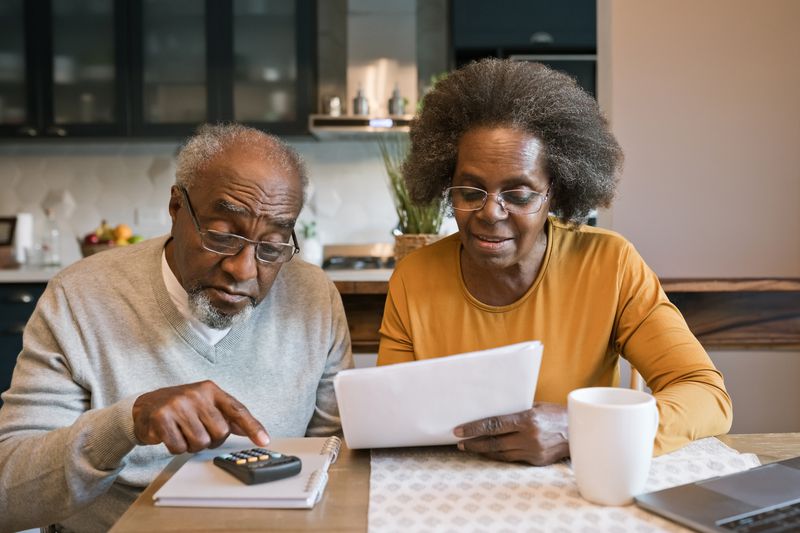 Senior woman and man sitting at the table at home and going through bills.