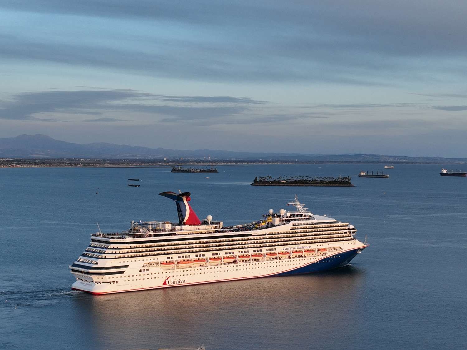 An aerial view of the Carnival Radiance, a Destiny-class cruise ship, as it heads out to sea in Long Beach at sunset Friday, Feb. 17, 2023.