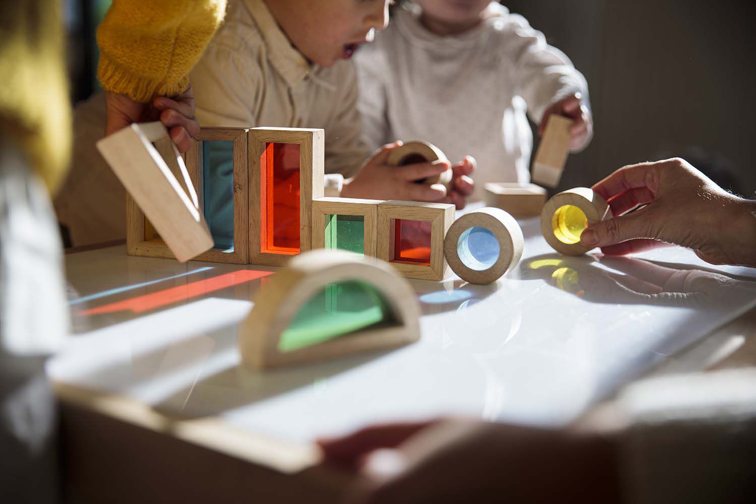 Little kids playing with colorful wooden building blocks on the table at home daycare