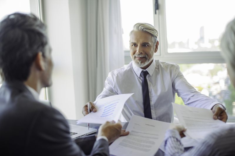 An executive hands a client paperwork.