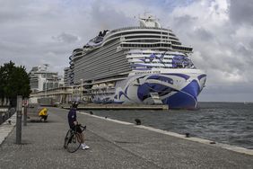 A biker looks at a Norwegian cruise ship