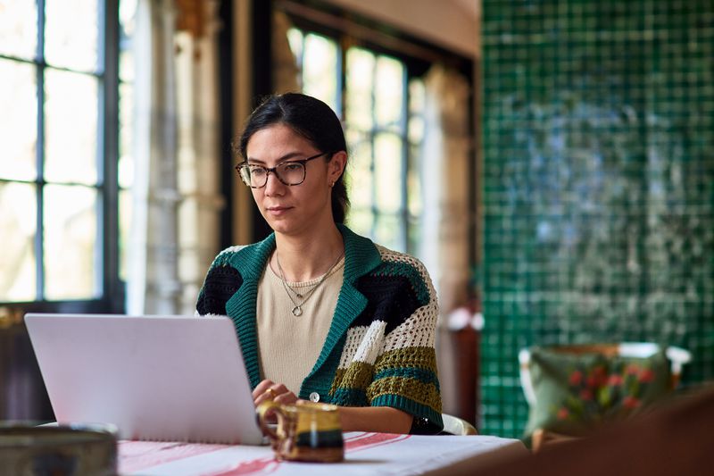 Woman in her home office looking at laptop and working.