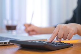 A business woman using a calculator to calculate the numbers on his desk in a office.