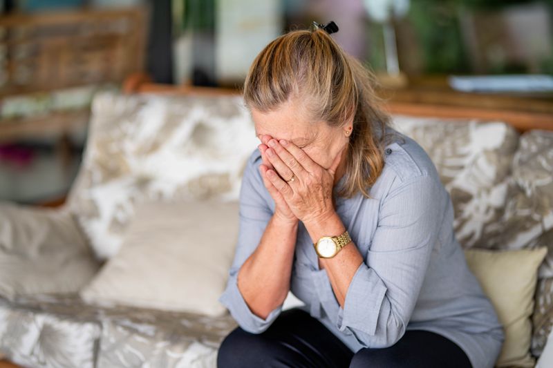 Woman on couch with her head in her hands