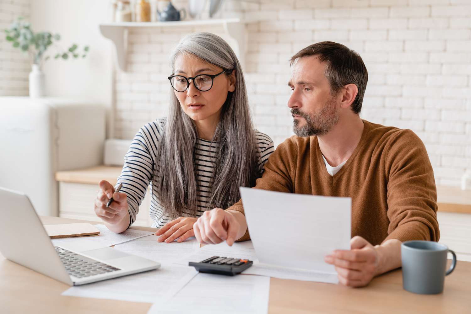 Middle-aged couple reviewing finances on computer at home
