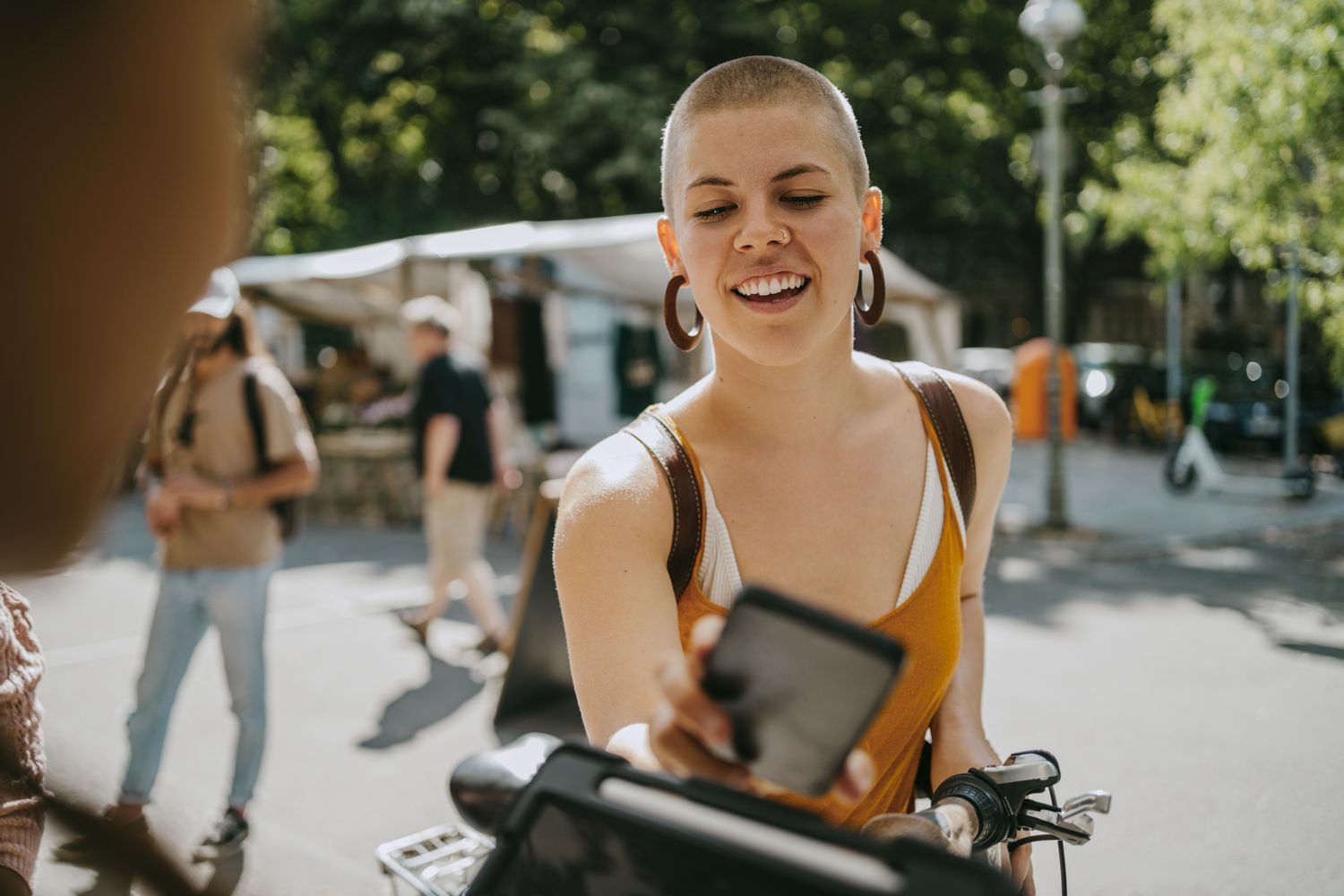 A person pays at an outdoor market using their mobile phone. 