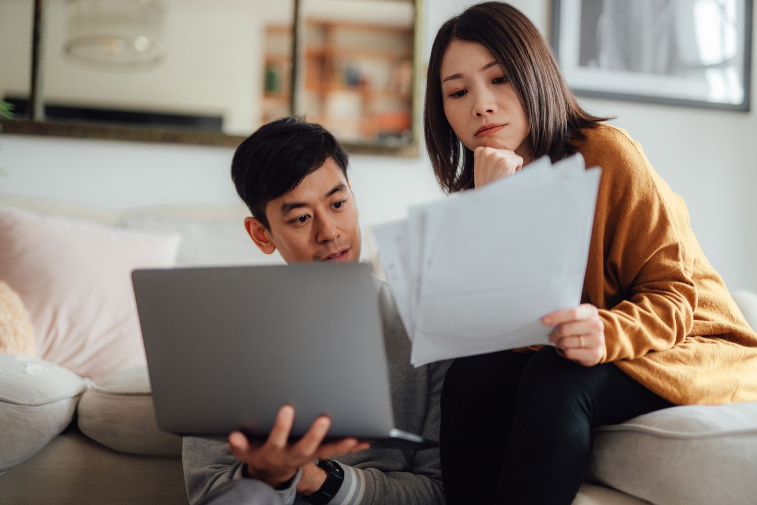 A couple reviews finances while sitting on the couch.