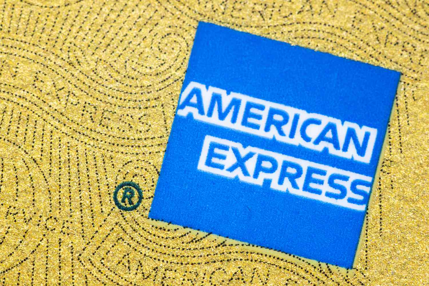 The blue American Express logo is seen on a gold credit card.