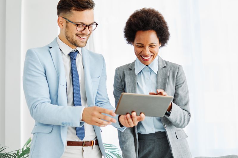 Two people in suits looking at a tablet