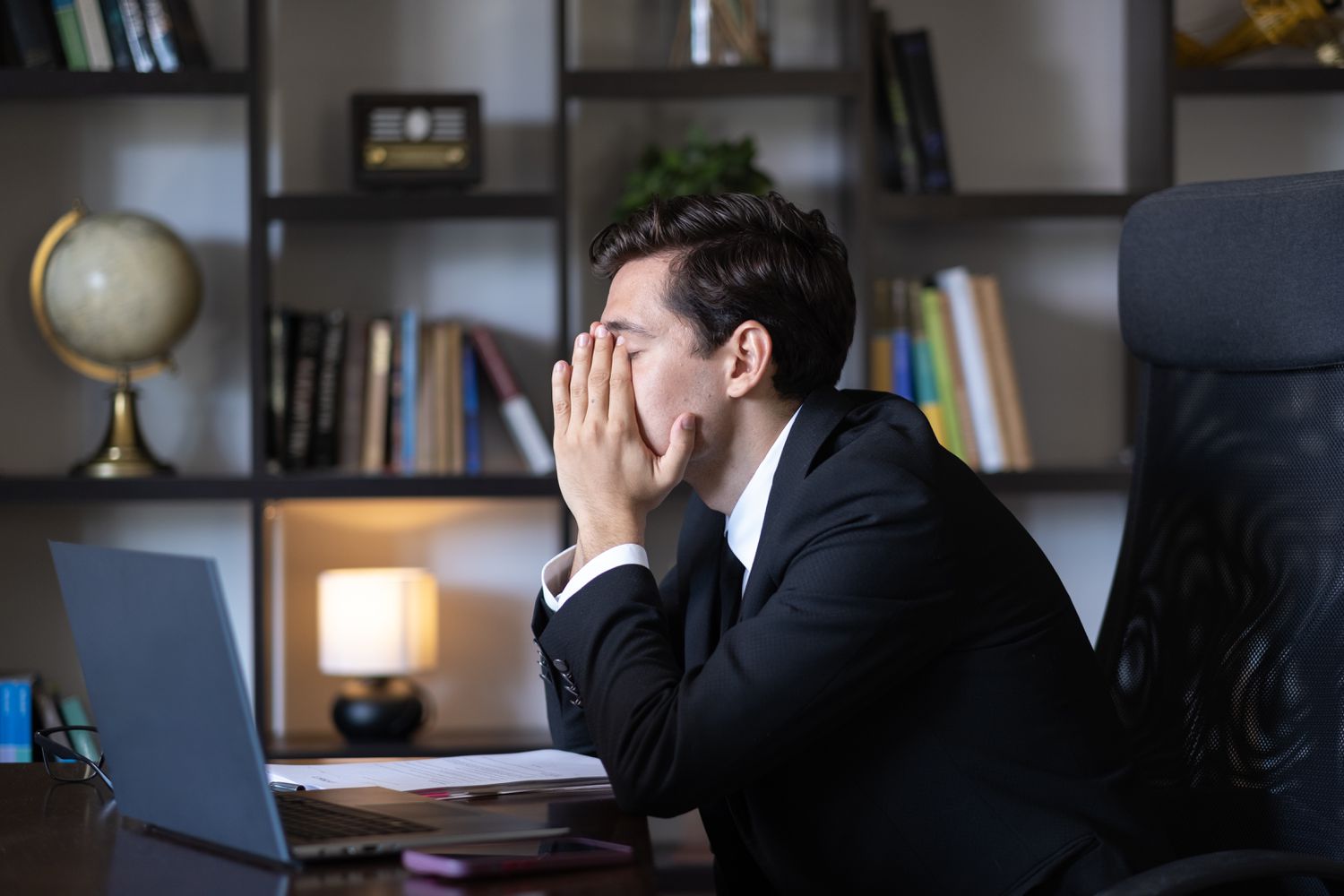 A man in a suit with his head in his hands