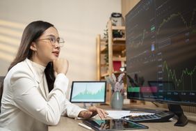 A forex trader in works on computer screen and tablet to judge profitable trades.