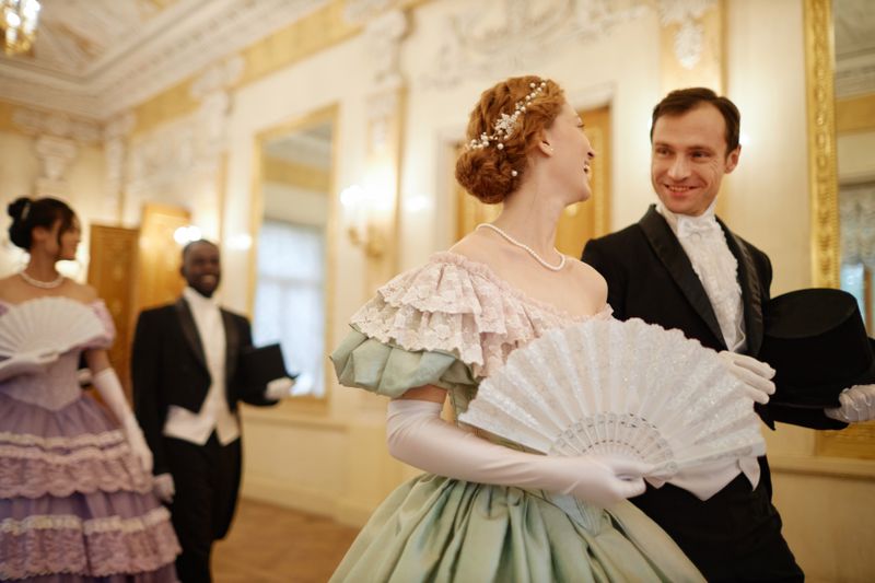 Waist up portrait of elegant couple of lady and gentleman chatting cheerfully walking in palace hall