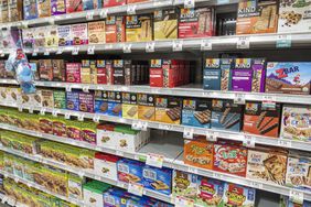 Boxes of cereal and granola bar line the shelves of a supermarket.