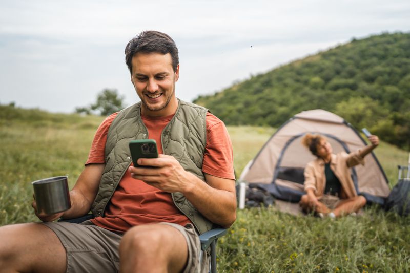 Camping couple using mobile phones