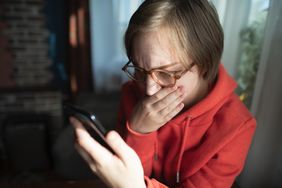 A person concerned about something looking at a smartphone.