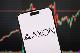 Logo of Axon Enterprise displayed on a smartphone screen with a stock market chart in the background