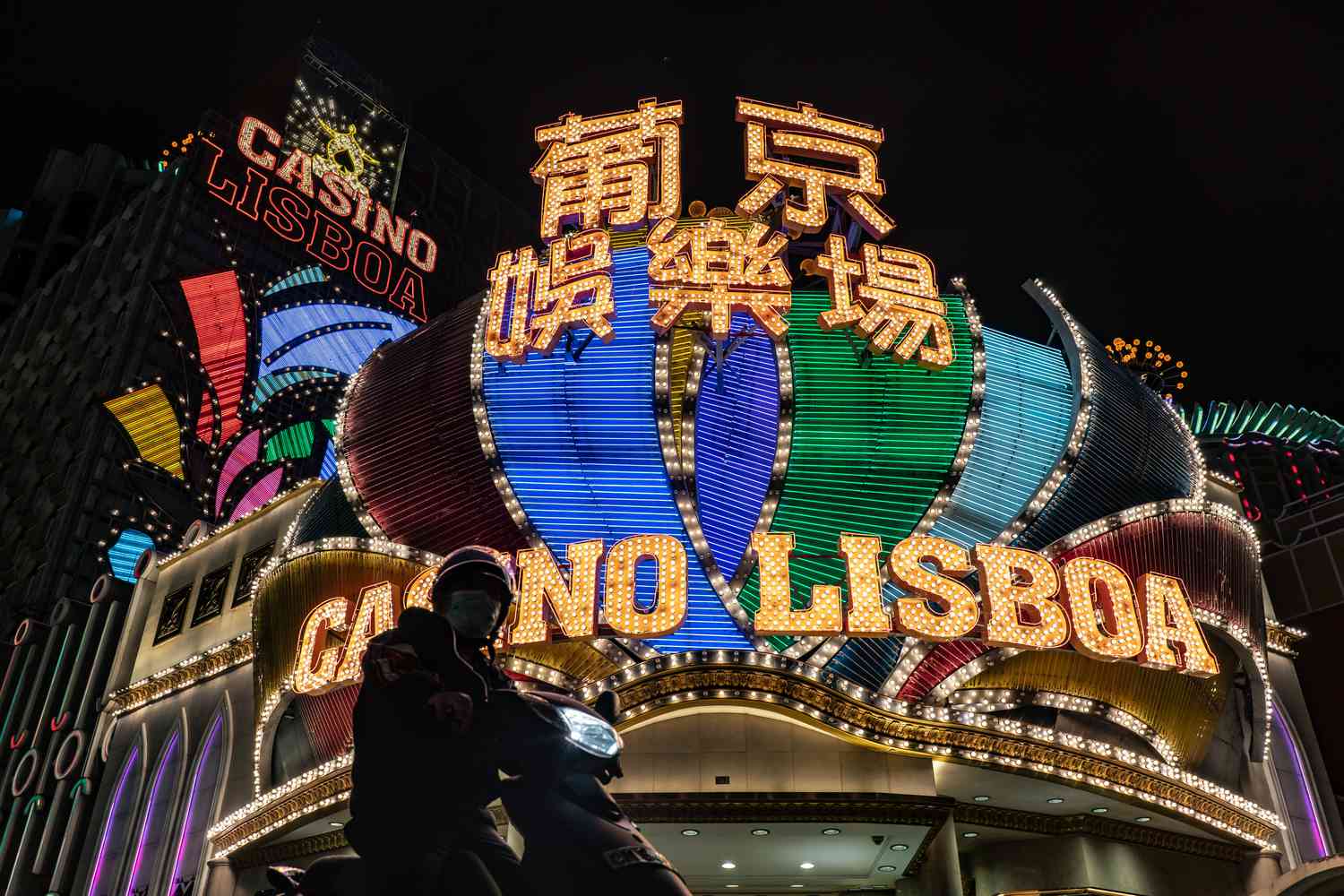 A motorcyclist stops for a traffic light in front of the Casino Lisboa.