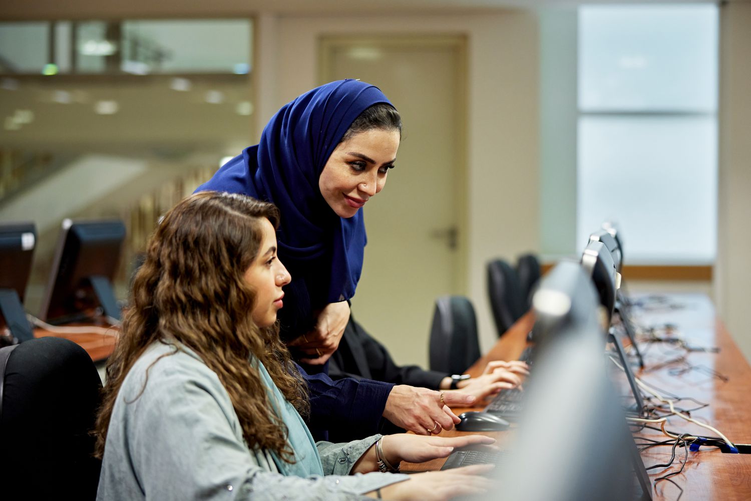 Two workers at a computer in a computer lab