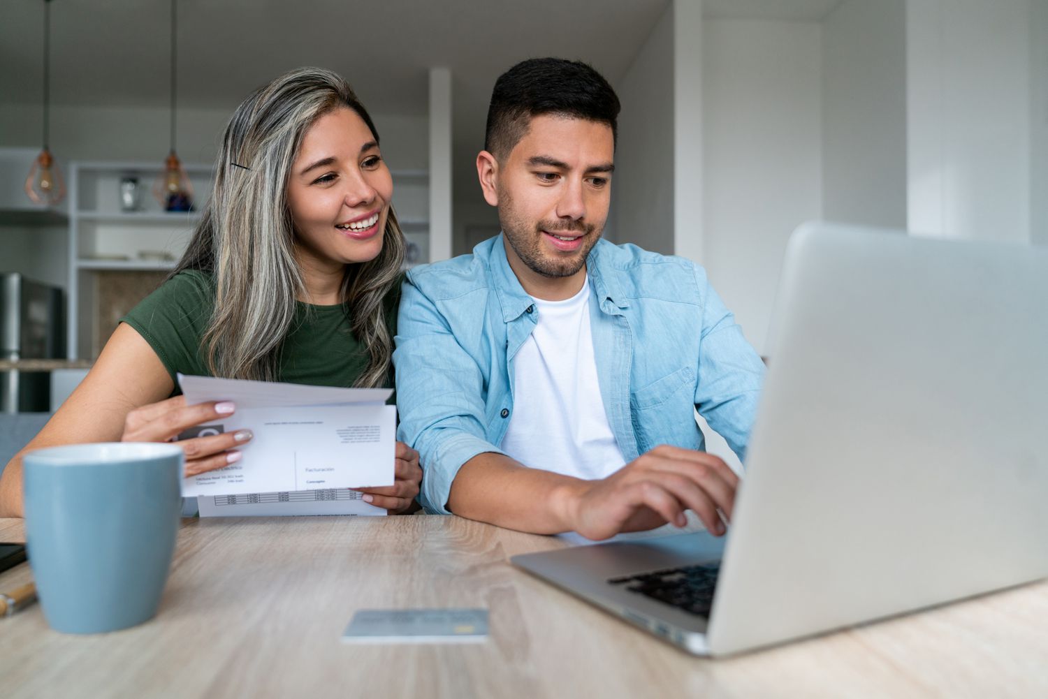 A couple sitting at home looking at different types of bank accounts on laptop.