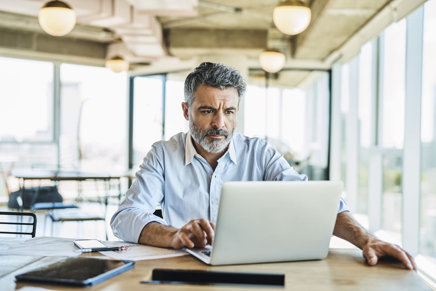 Mature man with beard looking intently at his laptop