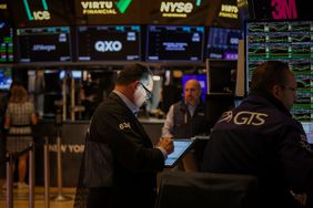 A man looks at a tablet while other traders work around him on the floor of the New York Stock Exchange.