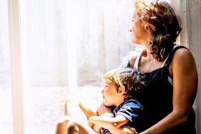 A mother and son looking out a window