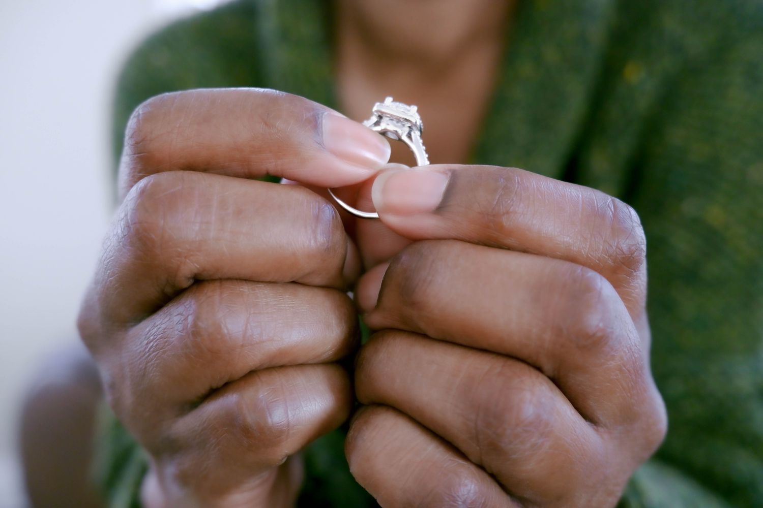 Close up of a Black woman's hands holding an engagement ring