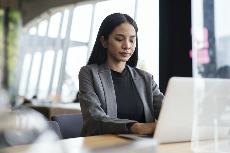 A woman types on a laptop in an office setting