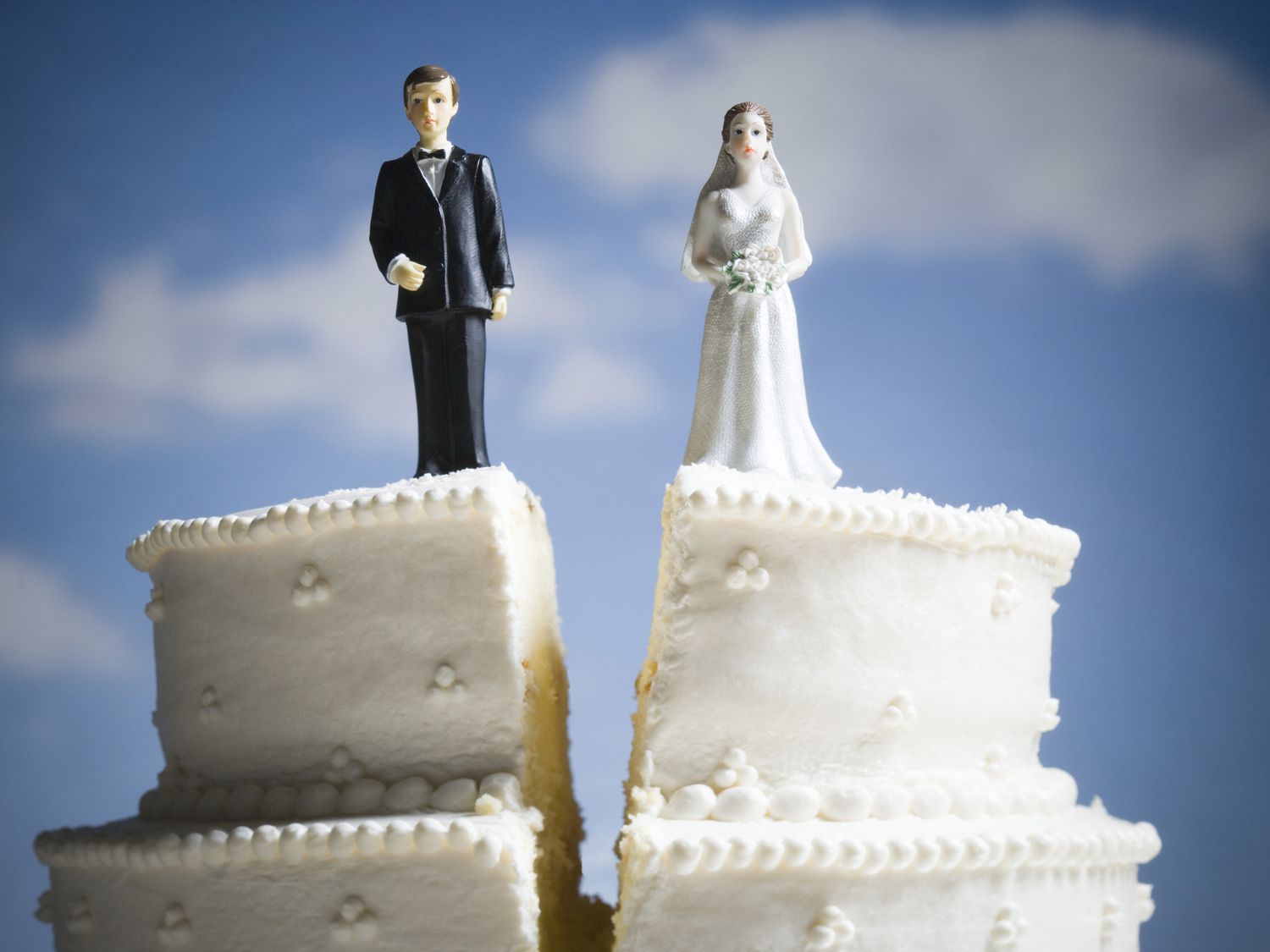 Wedding cake split in half with groom and bride figures on separate sides