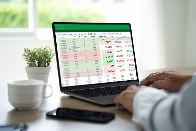 Person working with data and graphs in spreadsheet documents on a laptop computer in a home office